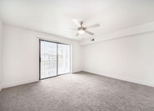 Living room with a ceiling fan and a slider to a balcony at Stoney Pointe Apartment Homes, Kansas