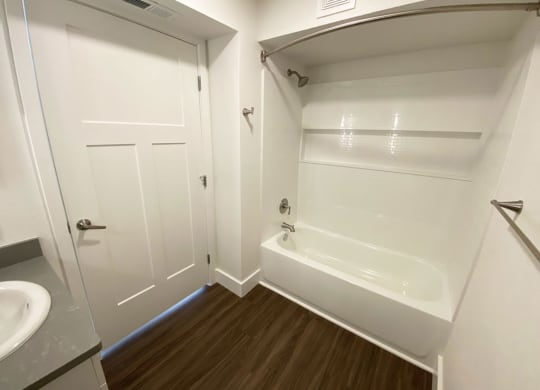 a bathroom with a tub and a sink and a door at Stoney Pointe Apartment Homes, Wichita