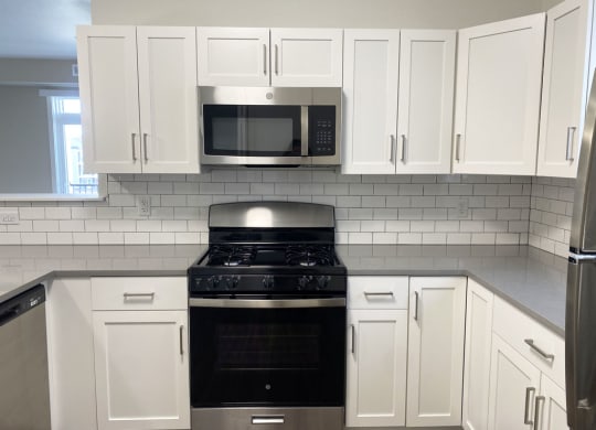 a kitchen with white cabinets and a stove and a microwave at Stoney Pointe Apartment Homes, Wichita, 67226