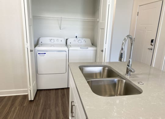 a kitchen with a sink and washer and dryer at Stoney Pointe Apartment Homes, Kansas
