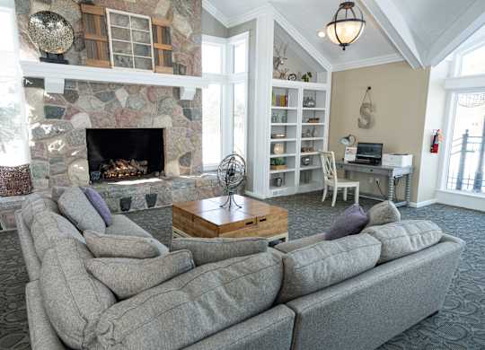A living room with a stone fireplace and a grey sofa.
