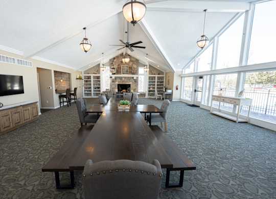 A large wooden table is surrounded by chairs in a spacious room with a fireplace.