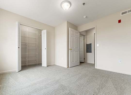 A bedroom with a carpeted floor and a walk-in closet at Stoney Pointe Apartment Homes, Kansas