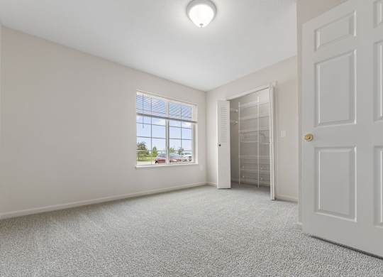 A bedroom with a window and a carpeted floor at Stoney Pointe Apartment Homes, Kansas