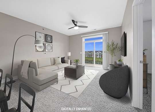A modern living room with a grey sofa, a black armchair, and a television on the wall.