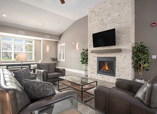 A community room with a fireplace and a television at Strathmore Apartment Homes, West Des Moines, IA