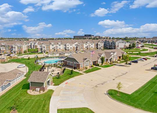 A large apartment community with a swimming pool and a flag flying in the breeze at Strathmore Apartment Homes, Iowa