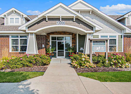 The front of a brick leasing office building with landscaping in front at Strathmore Apartment Homes, Iowa