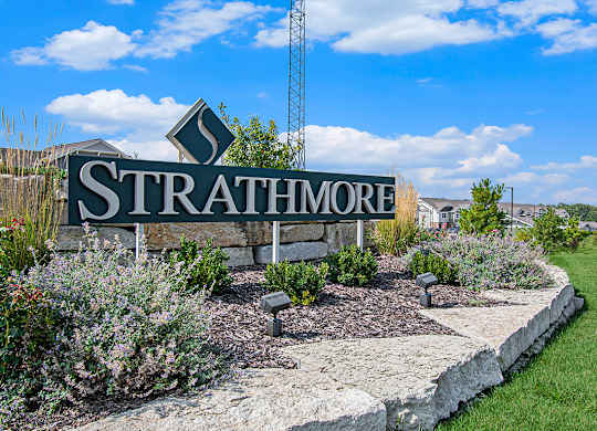 A sign that says Strathmore is in front of a grassy area at Strathmore Apartment Homes, Iowa