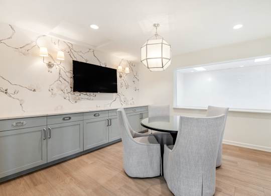 A modern living room with a television, grey armchairs, and a marble backsplash. at Sundance Apartments, Indiana, 46237