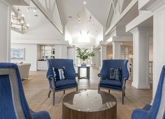 A modern living room with blue chairs and a glass table. at Sundance Apartments, Indianapolis, Indiana