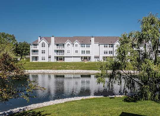 A large white building with a grey roof is situated next to a body of water. at Sundance Apartments, Indiana, 46237