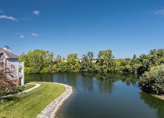 A serene landscape with a house, a lake, and a winding path. at Sundance Apartments, Indianapolis, 46237