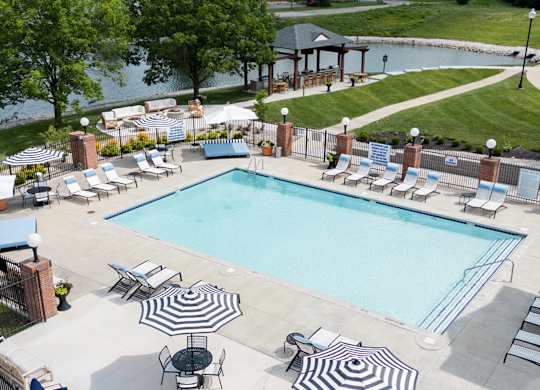 A large outdoor swimming pool surrounded by lounge chairs and umbrellas. at Sundance Apartments, Indianapolis, IN, 46237