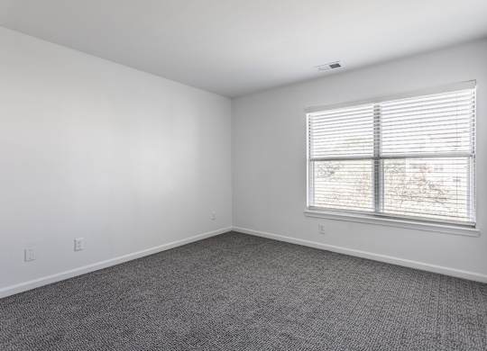 A room with a window and a carpeted floor. at Sundance Apartments, Indianapolis