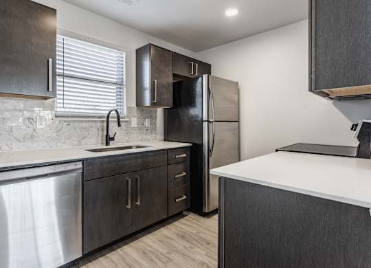 A modern kitchen with dark wood cabinets and stainless steel appliances. at Sundance Apartments, Indiana, 46237