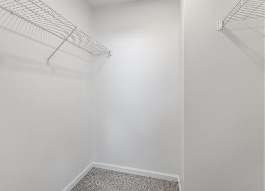 A white closet with a carpeted floor and two metal racks. at Sundance Apartments, Indianapolis, IN