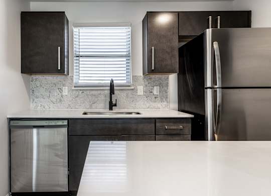 A modern kitchen with a stainless steel refrigerator and a marble backsplash. at Sundance Apartments, Indianapolis, IN, 46237