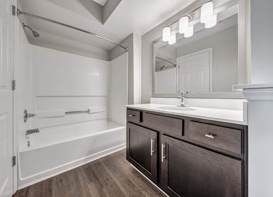A bathroom with a white tub, sink, and mirror. at Sunscape Apartments, Virginia
