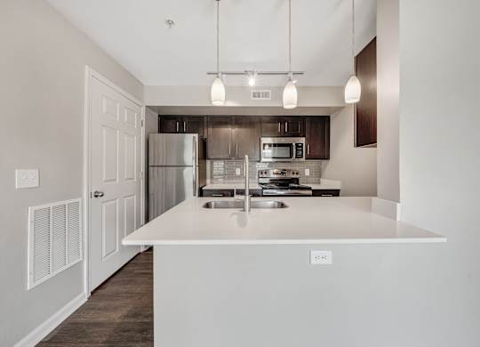 A modern kitchen with a white island and stainless steel appliances. at Sunscape Apartments, Roanoke