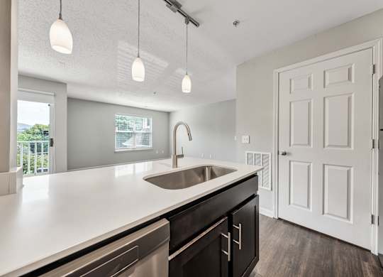A modern kitchen with a white countertop and a stainless steel sink. at Sunscape Apartments, Virginia