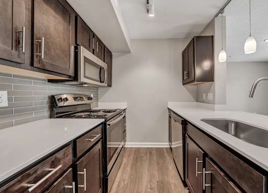 A kitchen with dark wood cabinets and a white countertop. at Sunscape Apartments, Roanoke, Virginia