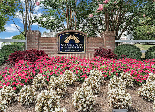 A sign for SunScape Apartments is surrounded by flowers. at Sunscape Apartments, Virginia, 24018