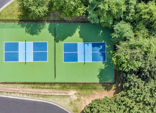 Two tennis courts surrounded by trees. at Sunscape Apartments, Virginia