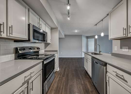 A kitchen with white cabinets and dark wood floors. at Sunscape Apartments, Virginia