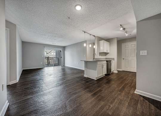 A kitchen with white cabinets and a wooden floor. at Sunscape Apartments, Virginia