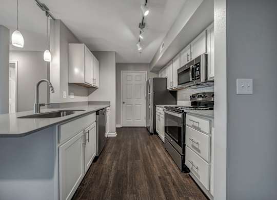 A modern kitchen with white cabinets and a wooden floor. at Sunscape Apartments, Virginia, 24018