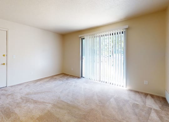 an empty living room with a sliding door to a patio at Swiss Valley Apartments, Wyoming, MI