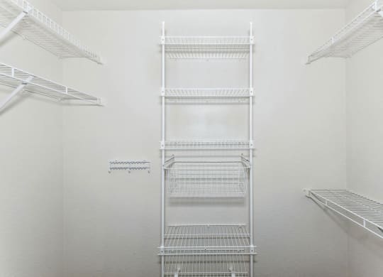 a walk in closet with white walls and white metal shelves at Tall Oaks Apartment Homes, Kalamazoo, 49009