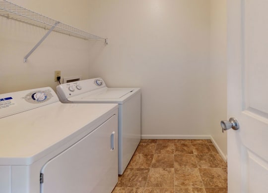 a washer and dryer in a laundry room with a white door at Tall Oaks Apartment Homes, Kalamazoo, 49009