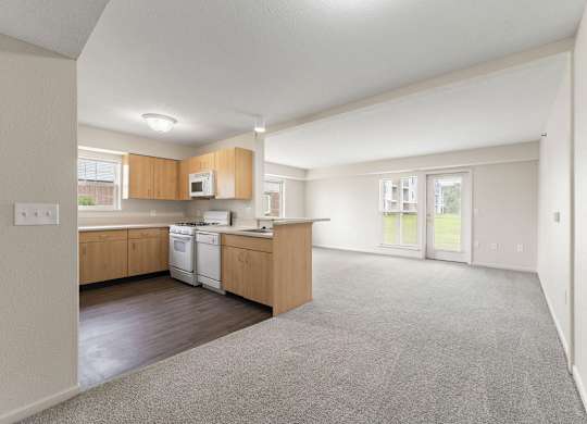 A spacious kitchen and enlarged living room leading to a patio at Tall Oaks Apartment Homes, Michigan, 49009