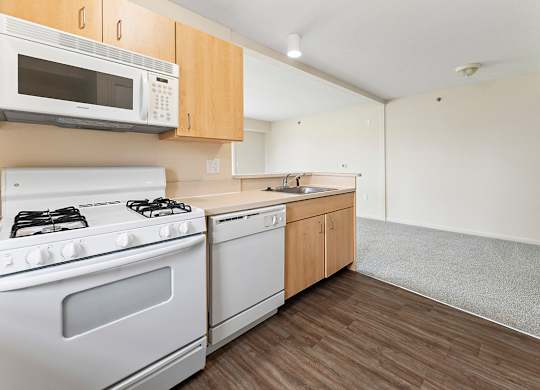 A kitchen with a white stove and microwave above it at Tall Oaks Apartment Homes, Michigan, 49009