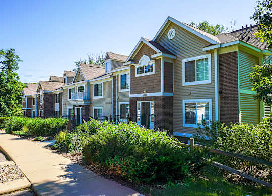 An exterior apartment building with green bushes in front at Tall Oaks Apartment Homes, Kalamazoo, MI, 49009