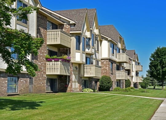 an apartment building on a sunny day with a grassy area in front of it at Tanglewood Apartments, Oak Creek, Wisconsin