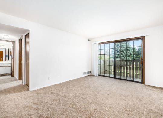 an empty living room with a large window and carpeting at Tanglewood Apartments, Wisconsin