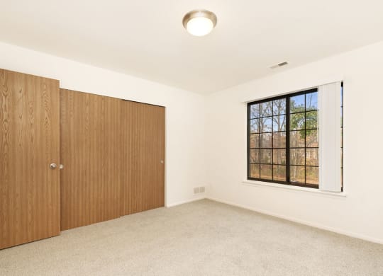 an empty bedroom with a window and a door at Tanglewood Apartments, Oak Creek