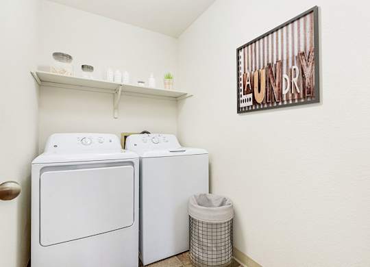 A laundry room with a washer and dryer and a shelf at Tanglewood Apartments, Oak Creek