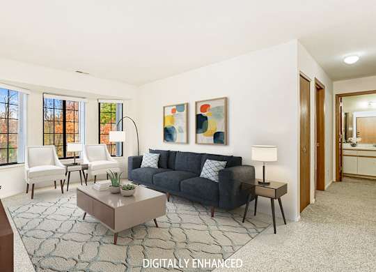 A living room with bay windows and grey couch at Tanglewood Apartments, Oak Creek