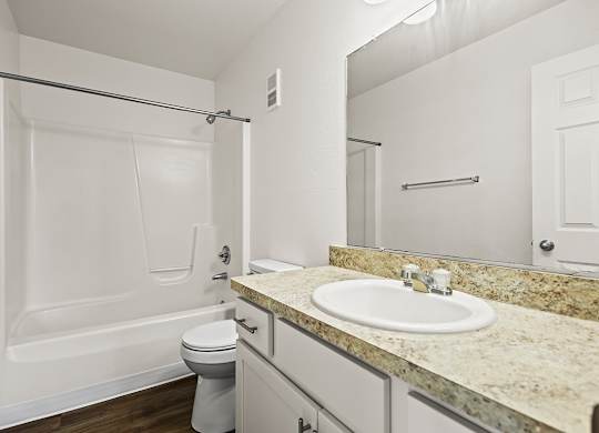A white bathroom with a sink, toilet, and bathtub at Tanglewood Apartments, Oak Creek, WI