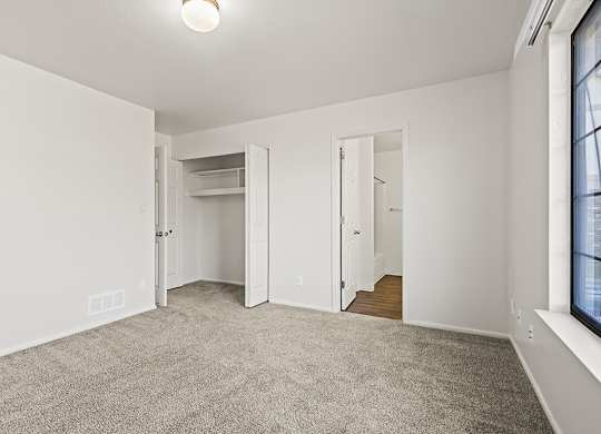 A bedroom with a carpeted floor and white walls at Tanglewood Apartments, Oak Creek, WI
