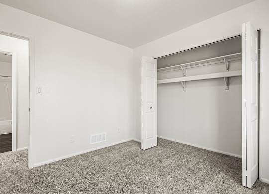 A white bedroom with a closet and carpeted floor at Tanglewood Apartments, Oak Creek, WI