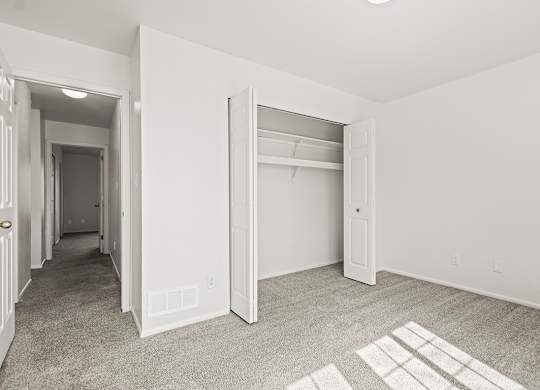 A bedroom with a carpeted floor and a white closet at Tanglewood Apartments, Oak Creek, WI