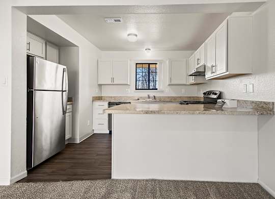 A kitchen with a stainless steel refrigerator, window, and white cabinets at Tanglewood Apartments, Oak Creek, WI