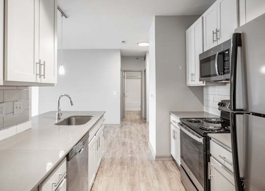 A modern kitchen with stainless steel appliances and wooden floors.