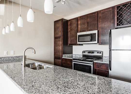 A kitchen with a granite countertop and stainless steel appliances.