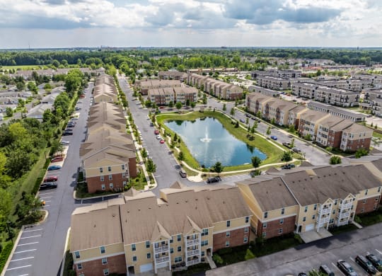 an aerial view of an apartment community with a pond in the middle at The Avenue at Polaris Apartments, Ohio